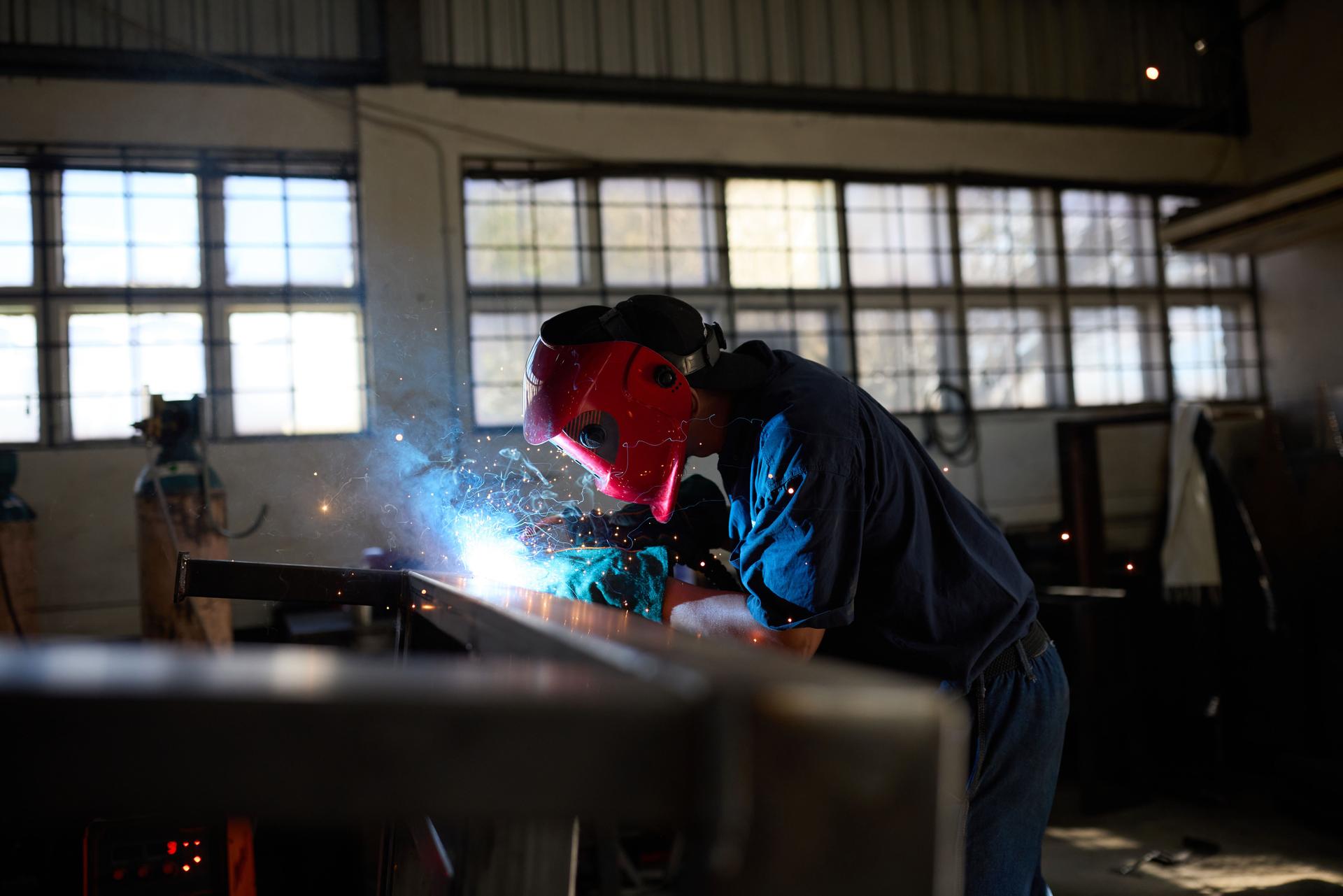 Industrial welder working on steel framework in a factory environment