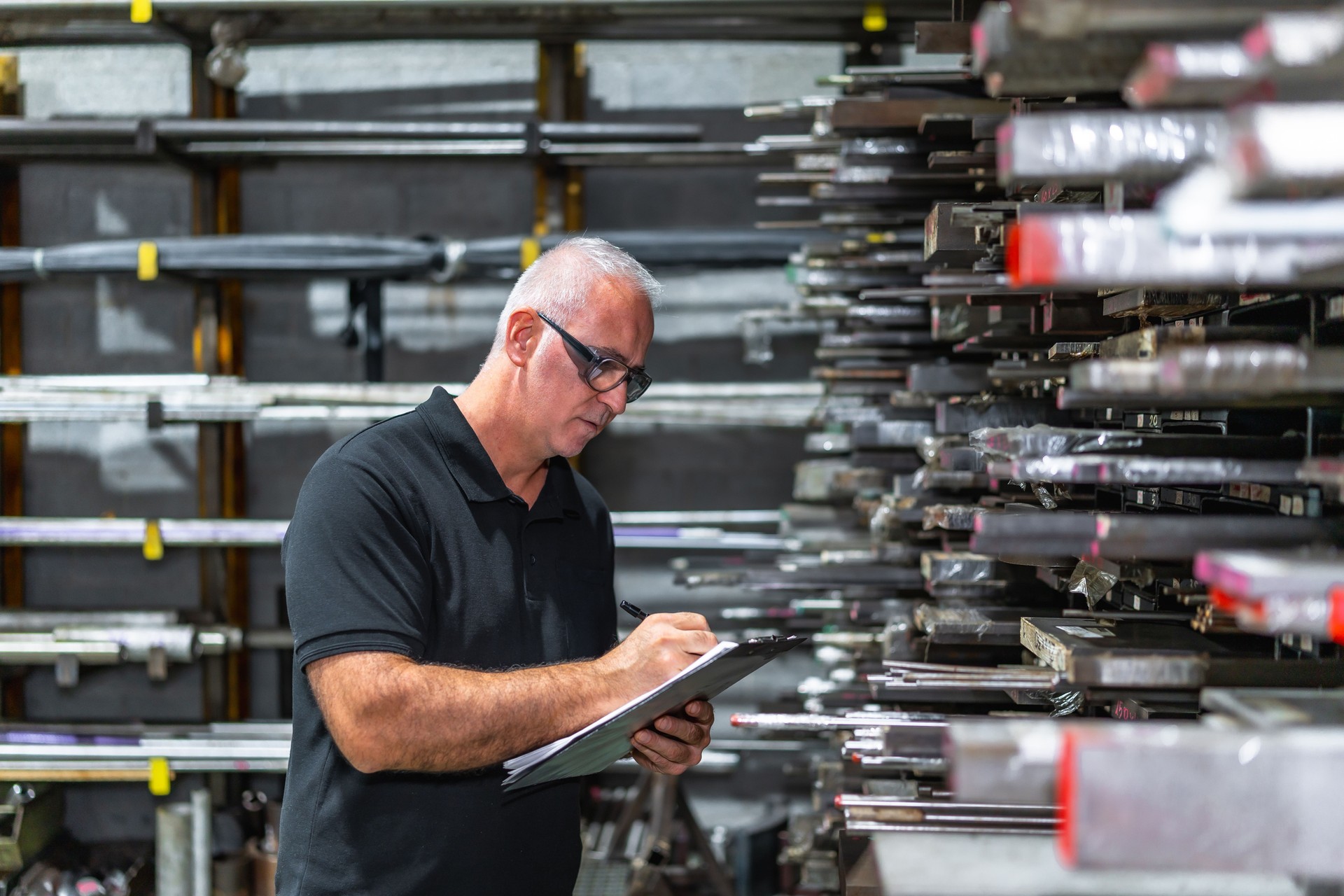 Man checking metal bars while doing inventory in a factory
